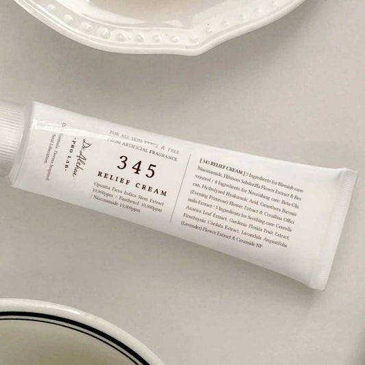 Un tubo blanco con la etiqueta Dr. Althea 345 Relief Cream de Bemba, ideal para piel sensible, con detalles de los ingredientes en texto negro, descansa sobre una superficie clara junto a un plato blanco. Perfecto para hidratación y regeneración gracias a su fórmula en gel.