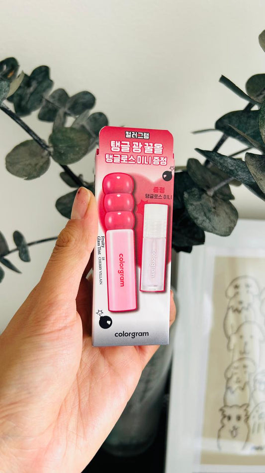Una mano sostiene un set de tintas Colorgram + mini brillo con tubos rosas y blancos, perfecto para labios suaves y un color vibrante. 